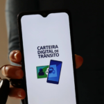 homem-segura-chave-e-com-a-mesma-mao-segura-um-celular-com-a-tela-do-aplicativo-carteira-digital-de-transito